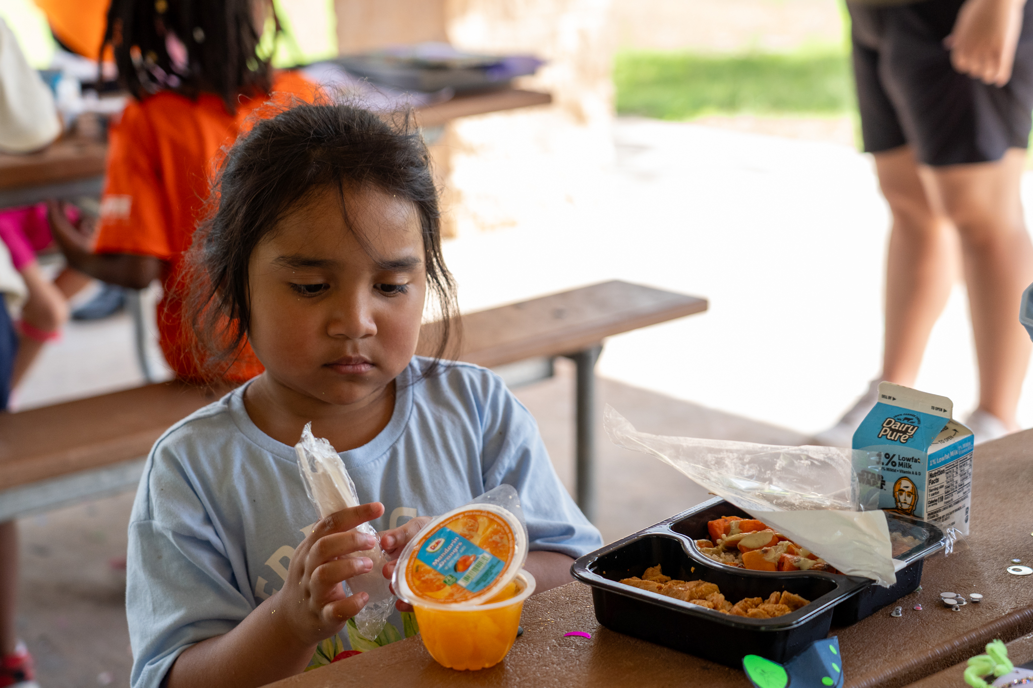 A girl in Austin is eating a free summer meal provided by the Central Texas Food Bank.